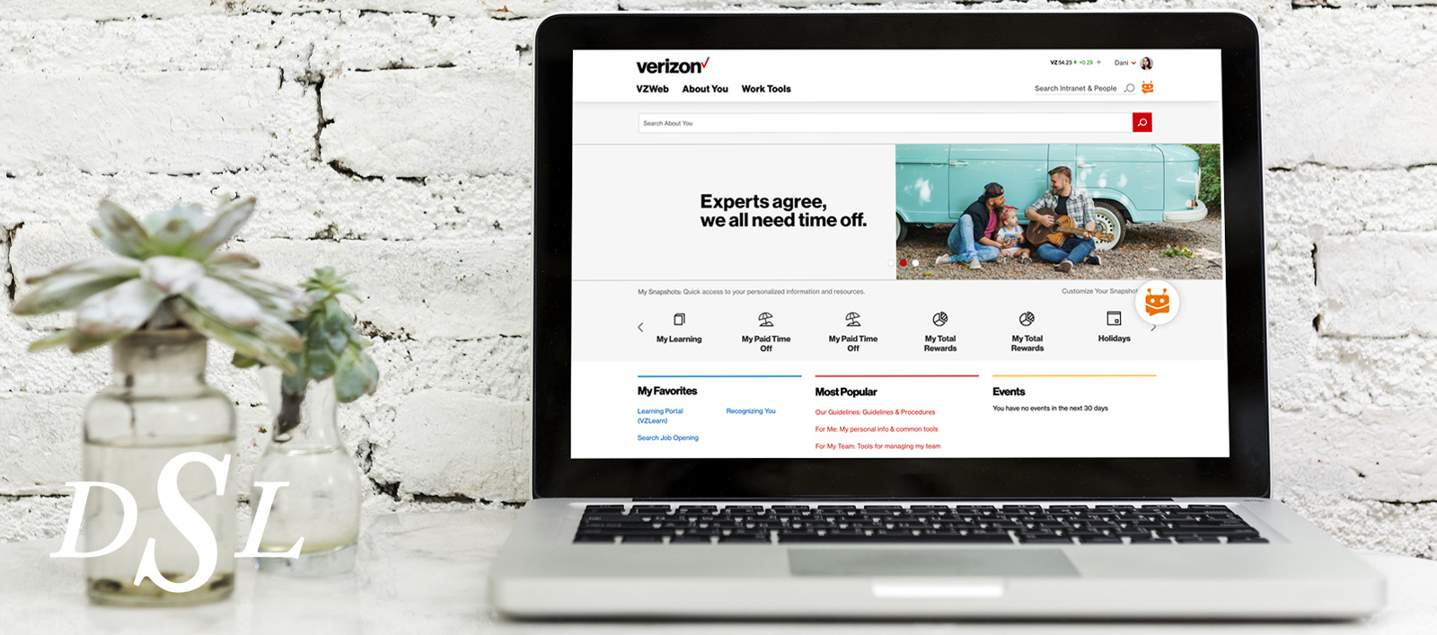 A laptop displaying an About You page banner next to plant vases.